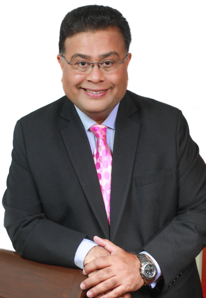 CFP® Taresh Bhatia, seated, wearing a black suit and pink tie